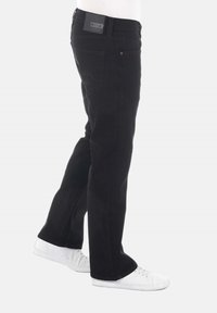 Pantalones vaqueros negros de mezclilla con un diseño de pierna recta, estilo de cinco bolsillos, que cuentan con una cinturilla de marca y detalles de costura mínimos. Llevados con zapatillas blancas.