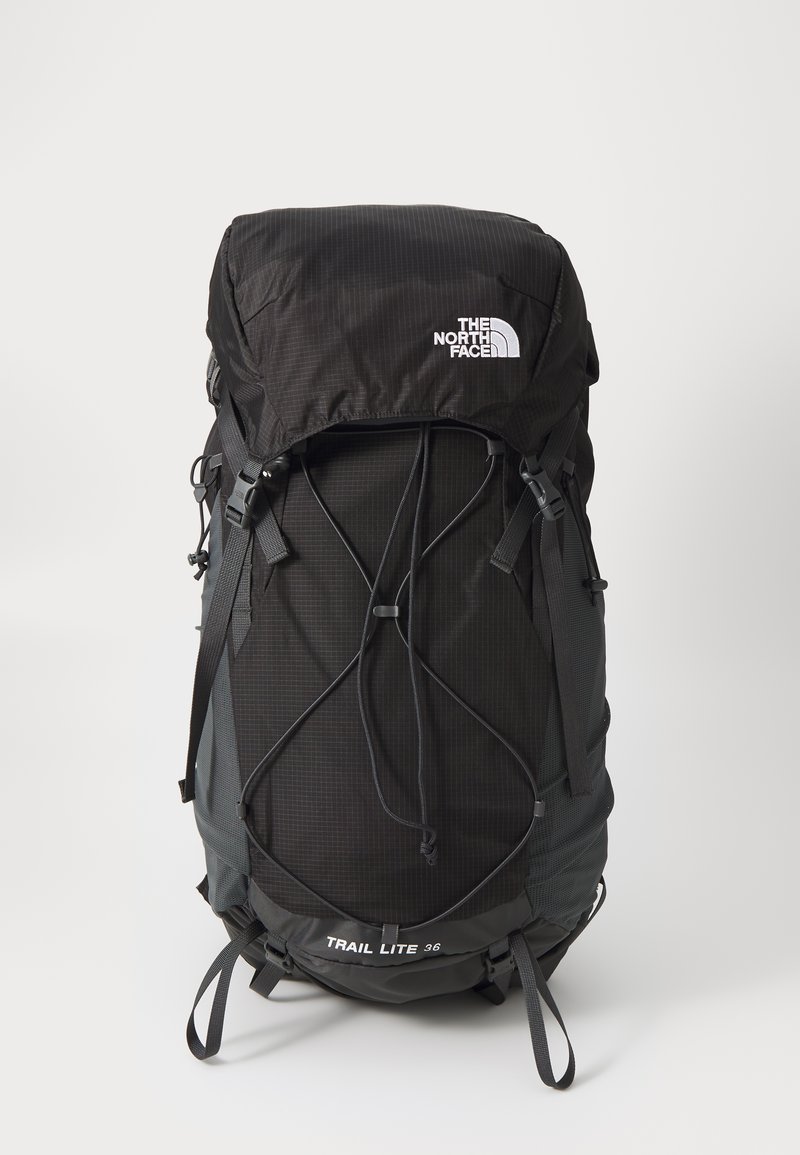 Sac à dos de randonnée noir avec des sangles ajustables, un rabat supérieur et un cordon élastique à l'avant. Présente le logo "THE NORTH FACE" et le texte "TRAIL LITE 36".