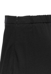 Sort nederdel med en glat tekstur, elastisk talje og en sidelukning. Stoffet er let med en subtil glans.