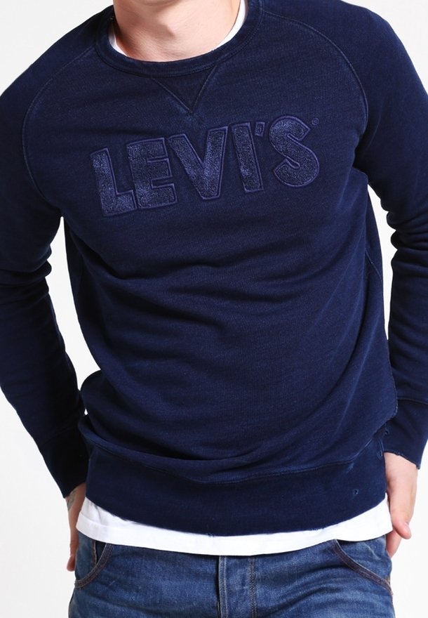 Sudadera azul marino con un logo texturizado de Levi's en la parte frontal, con un cuello y puños acanalados, usada sobre una camisa blanca.
