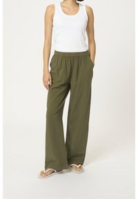 Pantalons larges vert olive avec une taille élastique et des poches latérales, associés à un débardeur blanc. Tissu léger et respirant.