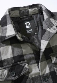 Juoda ir pilka languota marškiniai su apykakle, sagomis priekyje ir dviem krūtinės kišenėmis. Yra audinio etiketė su užrašu „Brandit“ ir dydis M.