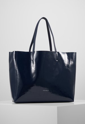 Błyszcząca ciemnogranatowa skórzana torba typu tote z dwoma uchwytami, prostokątną podstawą oraz małym logo marki umieszczonym na środku w pobliżu dołu.