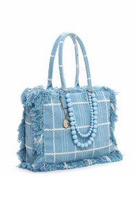 Niebieska pleciona torebka z białym wzorem w kratkę, frędzlami na krawędziach i zdobionym paskiem z koralików. Posiada dwa teksturowane uchwyty oraz metalowe ozdoby.