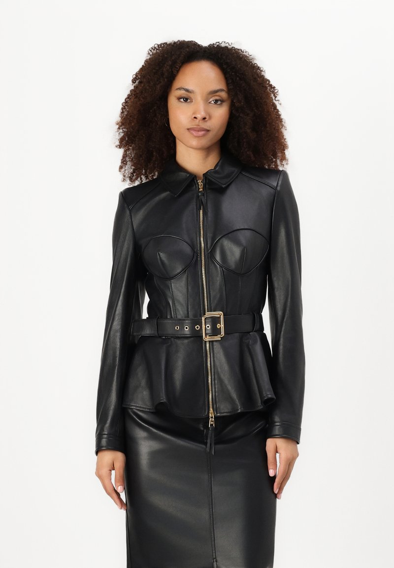 Giacca in pelle nera con design a peplo, dotata di zip frontale, colletto e due dettagli a forma di coppa sul petto. Accenti in metallo color oro.