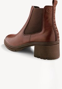 Botte Chelsea en cuir marron avec panneau latéral élastique, talon empilé épais, semelle texturée et languette de traction avec détail de couture à l'arrière.