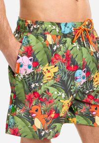 Plavky s živou tropickou potlačou s postavičkami Pokémon. Sú vyrobené z ľahkého materiálu, majú elastický pás a postranné vrecká.