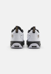 Czarne i białe buty sportowe z teksturowanej skóry, czarnymi akcentami oraz złotym logo na pięcie. Gruba gumowa podeszwa z bieżnikiem.