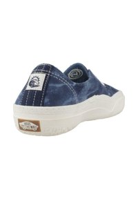 Zapato lona de marina tipo slip-on con suela de goma blanca, que presenta acentos cosidos y un parche con el logo en el talón. Parte superior texturada con forma redondeada.