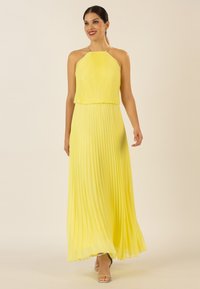 Gelbes, plissiertes Maxikleid mit Halterneck und mehrlagigem Oberteil, das einen silbernen Akzent am Halsbereich aufweist. Glattes, leichtes Material.