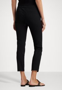 Zwarte cropped pantalons met een gladde textuur, voorzien van twee achterzakken. Gemaakt om te dragen met platte sandalen, met een aansluitend ontwerp.