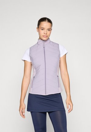 Gilet sans manches violet clair avec un col haut, design matelassé, fermeture éclair et deux poches latérales. Porté par-dessus un t-shirt blanc.