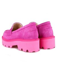 Klarröda mockaloafers med tjocka, chunky sulor och räfflad sula, visade från en bakre snedvy mot en vit bakgrund.