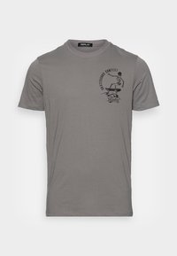 T-shirt gris à manches courtes en coton, avec un graphisme noir représentant un squelette faisant du skateboard à l'avant. Texture douce et coupe standard.