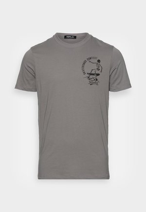 T-shirt gris à manches courtes en coton, avec un graphisme noir représentant un squelette faisant du skateboard à l'avant. Texture douce et coupe standard.