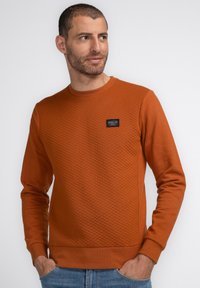 Ruitvormige, rustkleurige sweatshirt met textuur, ronde hals, geribde boorden en een klein zwart label op de borst. Casual fit.