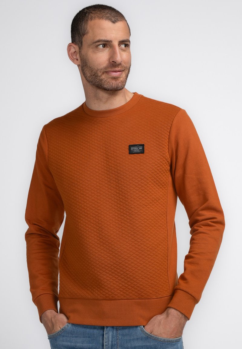 Ruitvormige, rustkleurige sweatshirt met textuur, ronde hals, geribde boorden en een klein zwart label op de borst. Casual fit.