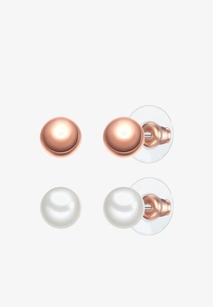 Dve kljucnice: ena bakrenega odtenka, okrogla z leskom, in ena bela, sferična, prav tako z leskom, obe pritrjeni na prozornih podložkah.