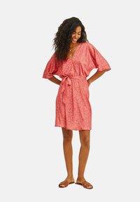 Krátké růžové šaty s květinovým vzorem, výstřihem do V, krátkými rukávy a zavazováním v pase. Lehce vzdušný materiál s hladkou strukturou.