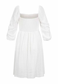 Vestido blanco con escote cuadrado, mangas largas abullonadas y cintura fruncida. Hecho de una tela texturizada, llega a la altura de la mitad de la pantorrilla.