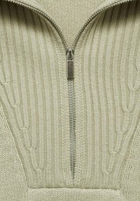 Knit pullover in light beige with a quarter-zip closure. Features ribbed texture and cable-knit pattern along the sides.