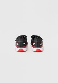Scarpe sportive nere e rosse con una parte superiore testurizzata, intersuola bianca e suola in gomma; presentano loghi sui lati e un collare imbottito.