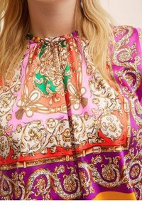 Blusa de seda colorida con un escote fruncido. El diseño incluye intrincados patrones de paisley en tonos de rosa, naranja, verde y acentos dorados.