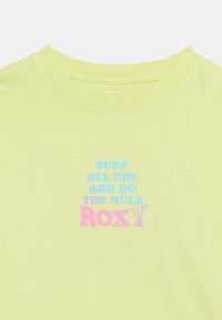 Ανοιχτόκκινο κίτρινο μπλουζάκι με στρογγυλή λαιμόκοψη που φέρει κείμενο σε  μπλε και ροζ: «Σέρφαρε όλη μέρα και κάνε το χούλα ROXY.»