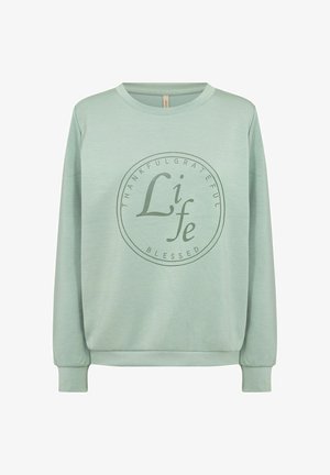 Világoszöld, hosszú ujjú pulóver, kerek nyakkivágással, amelyen kör alakú grafika található a "HÁLA", "KÖSZÖNET", "ÉLET" és "ÁLDOTT" szavakkal.