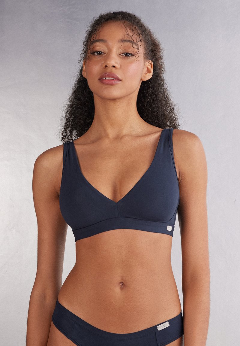 Marinebralette met een diepe V-hals, gemaakt van zachte stof. Heeft brede banden en een naadloos ontwerp, geaccentueerd met een klein logo label.