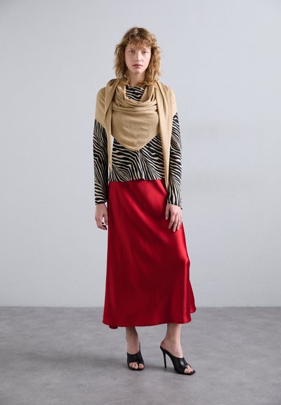Lunga gonna di raso rossa abbinata a una maglietta a strisce zebrate in bianco e nero. Sciarpa beige a strati, tacchi aperti neri. Design semplice ed elegante.