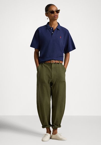 Μπλε κοντομάνικο πόλο με γιακά, πράσινο φαρδύ παντελόνι με τσέπες, ζώνη με σχέδιο, ανοιχτόχρωμα παπούτσια και γυαλιά ηλίου. Απλός, καθημερινός σχεδιασμός.