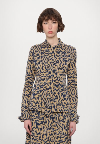 Blusa a maniche lunghe con colletto in un motivo astratto blu navy e beige. Tessuto leggero con chiusura a bottoni frontale e polsini arricciati.