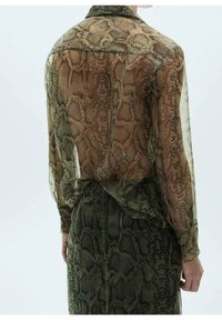 Przezroczysta bluzka w wzór wężowej skóry w odcieniach brązu i zieleni, z wykładanym kołnierzykiem i długimi rękawami, zestawiona z pasującą spódnicą.