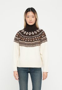Pulôver de malha com um alto gola alta, apresentando um yoke padronizado em castanho e branco. O corpo principal é de cor creme, com punhos e bainha canelados.