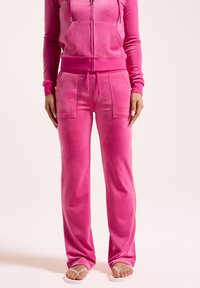 Roze velours trainingspak met een ritssluiting hoodie met zakken, bijpassende broek met voorzakken en sandalen. Zachte textuur en een ontspannen pasvorm.