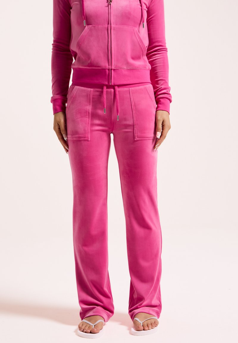 Roze velours trainingspak met een ritssluiting hoodie met zakken, bijpassende broek met voorzakken en sandalen. Zachte textuur en een ontspannen pasvorm.