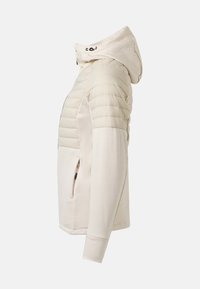 Veste à capuche beige avec manches supérieures et épaules matelassées, poche latérale zippée et tissu lisse sur les manches inférieures et les côtés.