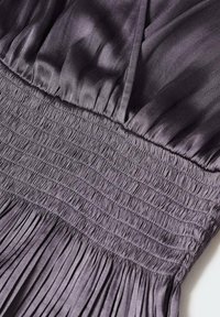 Lila Kleid mit einem gerafften Oberteil und einem plissierten Rock. Hergestellt aus einem glatten, leichten Stoff.