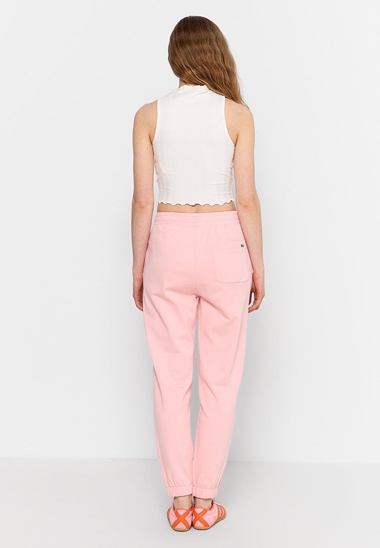 Roze joggingsbroek met elastische boorden en een achterzak; gecombineerd met een witte cropped tanktop met een gegolfde zoom.