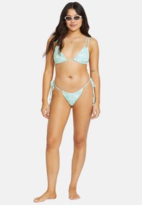 Bikini bleu clair avec imprimé floral, comprenant un haut triangulaire et un bas à lien sur les côtés. Fabriqué en tissu texturé, montrant un matériel minimal.
