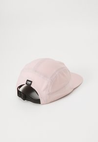 Lichtroze pet van ademend materiaal, met een gebogen rand en mesh-panelen, voorzien van een zwarte verstelbare strap aan de achterkant en een logo-tag.