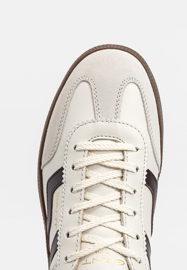 Weiße und beige Leder Sneaker mit braunen Streifen, cremefarbenen Schnürsenkeln und brauner Gummisohle, von oben betrachtet mit Fokus auf Zehen- und Schnürbereich.