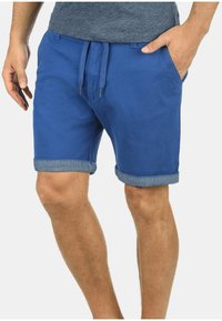 Shorts in cotone blu con vita regolabile, orli arrotolati e tasche laterali, caratterizzati da una texture liscia e un design informale.