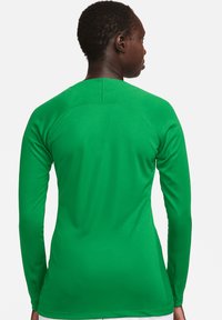 Grünes langärmliges Sportshirt mit glatter Textur. Hat einen runden Ausschnitt und ein Nahtdesign entlang des Rückens.