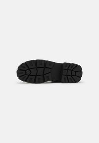 Black rubber shoe sole with deep treads and segmented pattern for traction; flat design, overall sturdy appearance suitable for various surfaces.