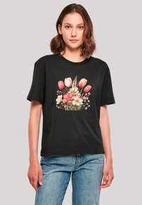 Black cotton t-shirt with short sleeves, featuring a floral print of tulips and blossoms in pink, white, and yellow at the center.