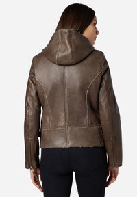 Brun läderjacka med huva, som har en slät yta, en tapered design och synliga sömnadsdetaljer. Dragkedja vid ärmsluten fulländar looken.