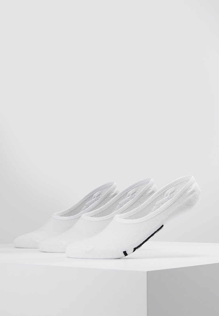 Calcetines de tobillo blancos, con un material ligero y transpirable, diseño bajo y un acento de logo negro en el lateral, exhibidos en fila.