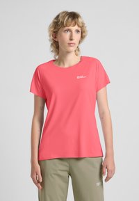 T-shirt a maniche corte, con scollo rotondo, di colore corallo brillante, realizzato in tessuto traspirante. Presenta un piccolo logo bianco sul petto.